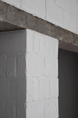 A zoom photograph of white painted, concrete block walls and a concrete lintel.