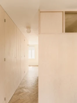 A corridor with parquet flooring and birch plywood timber panelling on the walls.