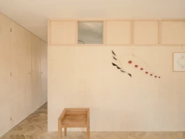 A house interior with oak floors, timber walls and a small wooden chair in the foreground.