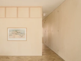 A house interior with parquet flooring, birch plywood panelling on the walls and a hanging picture.