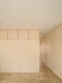 A photograph of an interior with parquet flooring and birch plywood panelling on the walls.