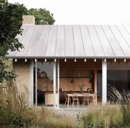 A house with a zinc roof, chimney and large sliding windows leading from a kitchen table.