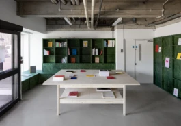 A bookshop with a large white table and green bookcases in the background.