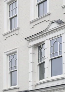 A historic façade with a bay, sash windows, cream brickwork and white painted stonework.