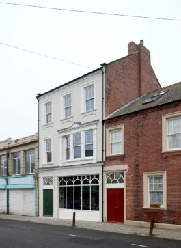 A view looking along a road with a renovated, Victorian pub and adjoining terraced houses.