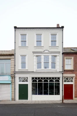 A renovated three storey Victorian pub with a bay window, cream brickwork and white painted stonework.