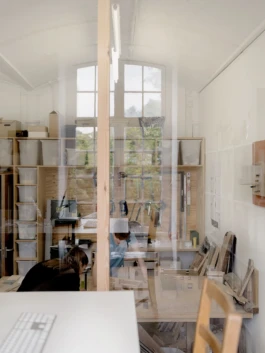 A view looking through a window to an architectural model making workshop.