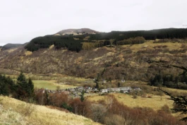 A view across a valley with a village below and mountains in the distance.