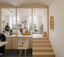 A studio with architectural models and timber stairs leading up to a mezzanine office space.
