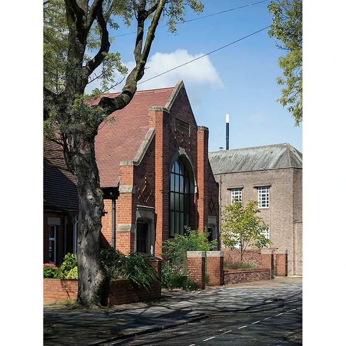 Topo Architects — A church converted into a home. The facade is red brick with a garden at the front.