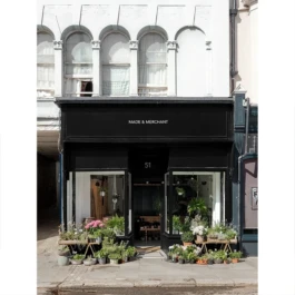 A renovated Victorian shop, now a florist with plants displayed outside and a black painted shopfront. 