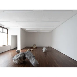 A contemporary art gallery with sculptures, a dark wooden floor and white walls. 