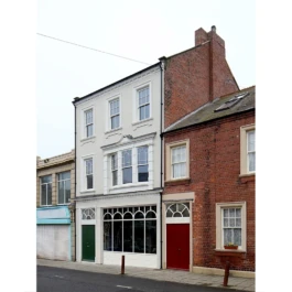 A view looking along a road with a renovated, Victorian pub and adjoining terraced houses. 