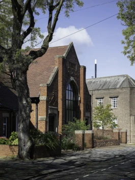 A church converted into a home. The facade is red brick with a garden at the front.