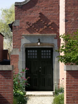 A converted church with a black painted door with flowers to the side.