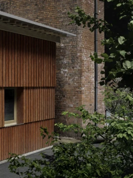 A red timber building next to a red brick wall.
