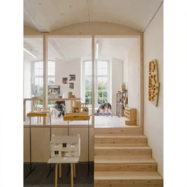 A studio with architectural models and timber stairs leading up to a mezzanine office space. 